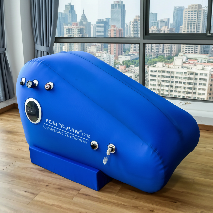 Blue hyperbaric chamber labeled 'Macy-Pan' on a wooden floor with a cityscape view through large windows.